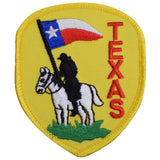 A shield-shaped embroidered patch with a depiction of a horse and cowboy, the Texas flag, and the word 'TEXAS' in red letters.