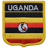 A shield-shaped embroidered patch with vertical stripes in yellow and red, featuring the text 'UGANDA' and an emblem of a bird, representing the flag of Uganda.