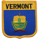 A shield-shaped embroidered patch with the text 'VERMONT' at the top and an emblem in the center, bordered by a gold-colored thread.